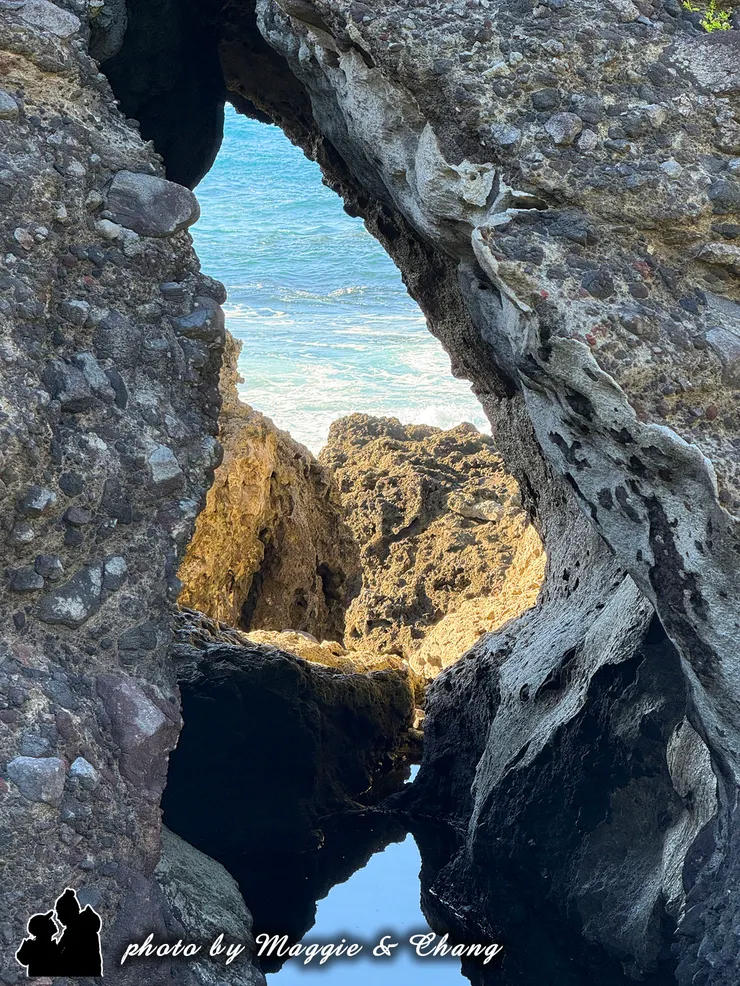 岩石縫隙透出海景的照片，藍綠色的海水配上粗獷的岩石紋理，層次感十足