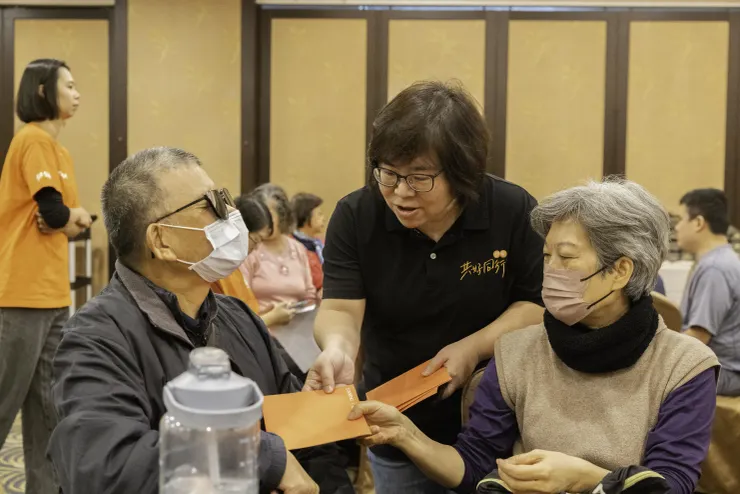 (圖說:伊甸台中區區長李思源(中)送上紅包予服務使用者白有東(左)。)