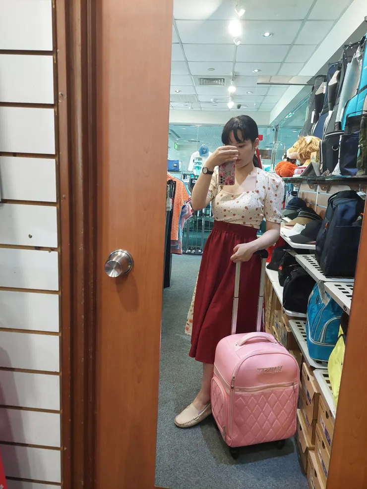 米黃色泡泡袖上衣，搭配手縫的紅色花布長裙，很適合跟粉色行李箱或粉紅色系物品合照