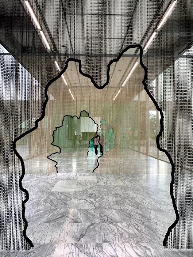 鍊簾背後的觀者身影被切割為透明與不透明的層層片段，像一道無形邊界，也像自由前的徘徊。(攝於北美館)