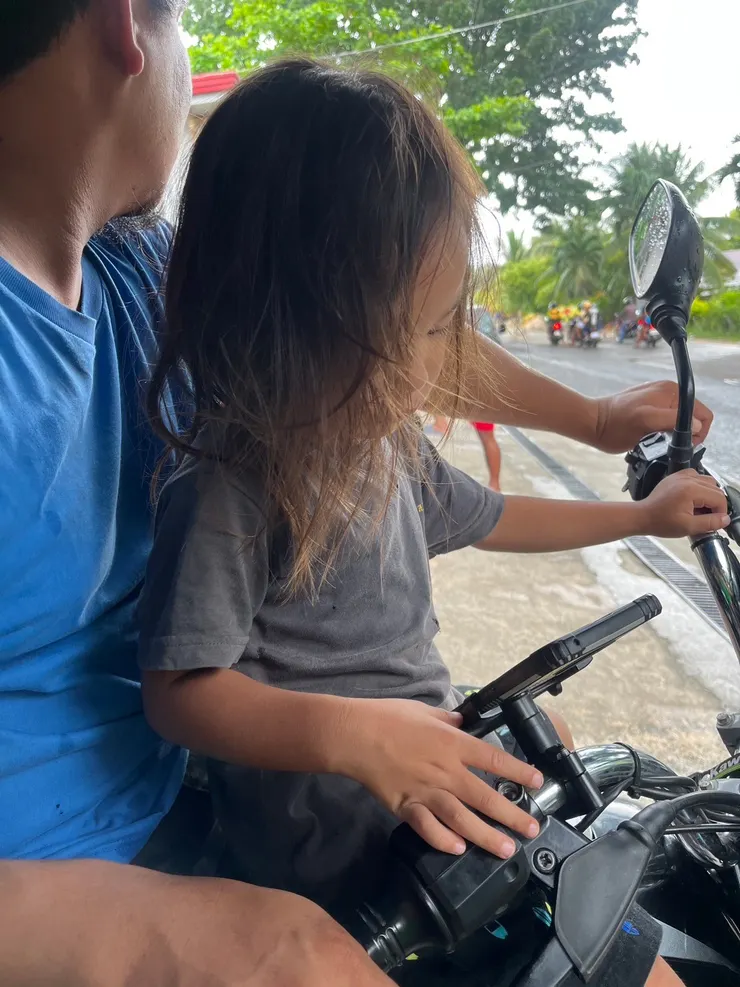 那邊的交通是三輪車，家長載著孩子，沒有安全帽是日常