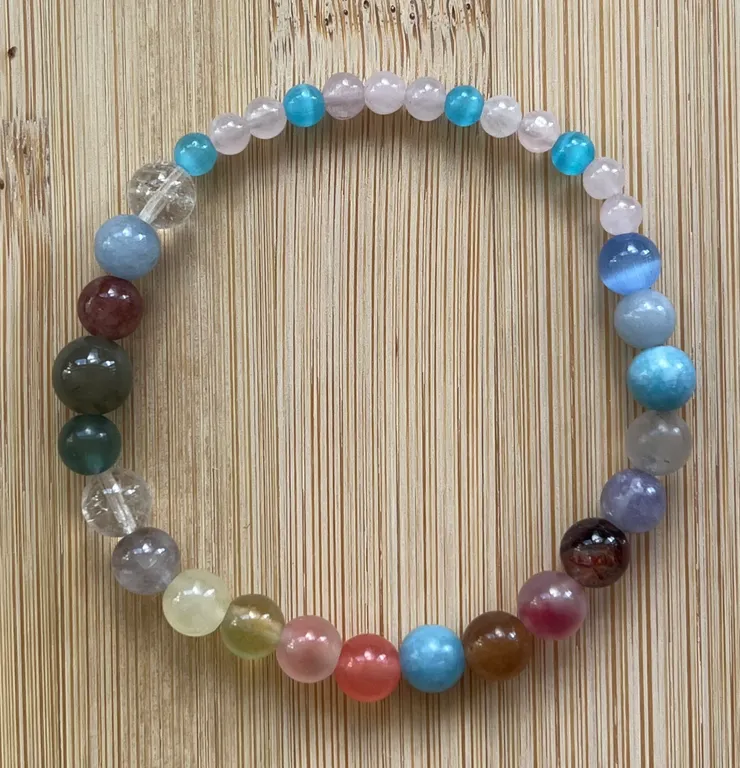 這條手鍊是我為她特別配的。 每一顆珠子都像是一個小小的提醒: 粉晶象徵自愛,藍色代表心境的平靜,彩色的串連則是她生命裡的多樣與力量。 我希望當她戴上它時,能想起—妳不必總是扛著堅強,也要學會對自己溫柔一點。