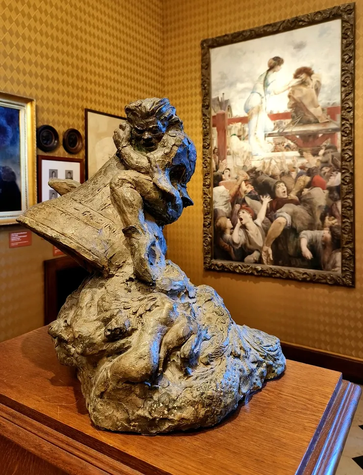 【雕塑應為「巴黎聖母院」的敲鐘人加西莫多，背後畫作為法國象徵主義畫家呂克-奧利維耶·梅森 (Luc-Olivier Merson) 所繪《愛斯梅拉達與加西莫多》 (Esmeralda and Quasimodo) 或名《一滴水換一滴淚》 (Une larme pour une goutte d'eau)。】