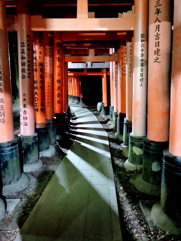 夜幕降臨，鳥居隧道裡只剩光與影的呼吸。每一步，都像走入夢與現實的縫隙。在這片橘紅的靜寂中，時間彷彿停下，只聽見心鼓動的回響。