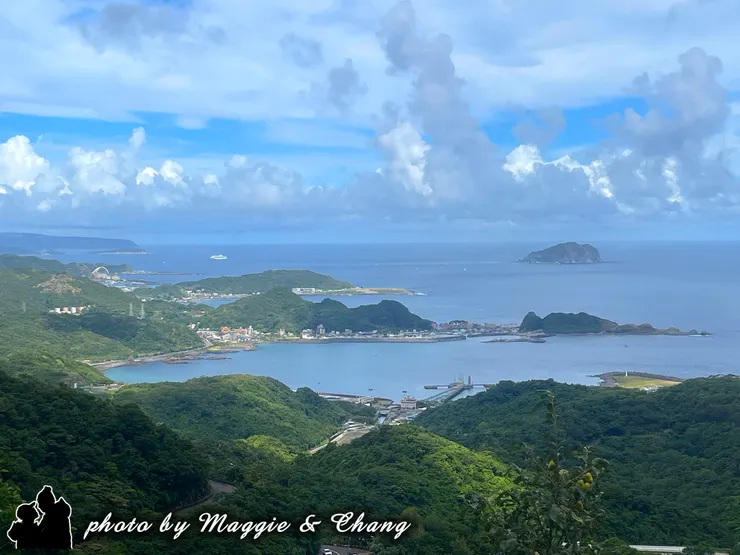 站在高處俯瞰，綠意層疊的山巒一路延伸到碧藍大海。港灣小鎮靜靜依偎在海邊，遠方基隆嶼像守護者般佇立，還有一艘白色郵輪點綴其間。天空雲朵翻湧，像在為這片海景鋪上柔和的濾鏡。💙  這一刻，什麼煩惱都隨著海風飄散，只留下心裡的平靜與自在。✨