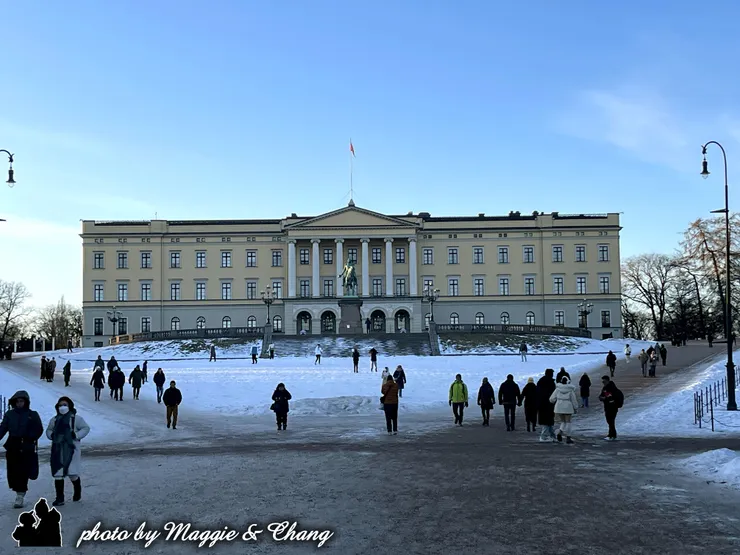 這座位於奧斯陸市中心的建築是挪威國王的官邸，建於19世紀，是新古典主義風格的建築。照片中你們在雪地上擺出歡樂的姿勢，背景就是氣勢恢宏的皇宮建築，前方還有一尊騎馬雕像，是國王卡爾·約翰的紀念像。