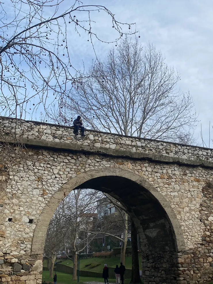 有一位黑色衣服的男子悠閒地坐在橋墩上，但有很害怕他會不會突然跳下來