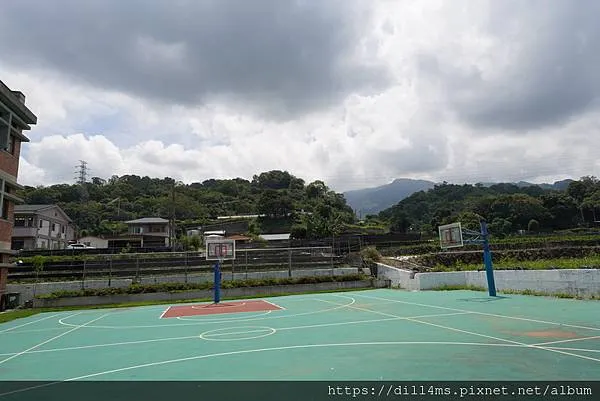 標準的籃球場一座，還有球架，背後看到的是一片梯田和草莓田
