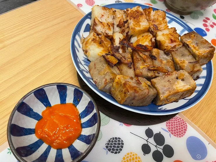 上方是蘿蔔糕，下方是芋頭糕，配上橙紅色的余均益辣椒醬。（作者拍攝）