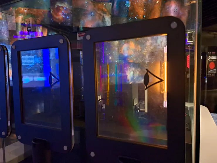 從偏光片的約45度角斜看，可見元素燈不同特徵的發射光譜。圖為氦氣燈所發出的發射光譜(攝於臺北天文館)