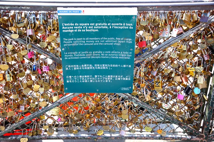 【聖心堂周邊圍欄的「愛情鎖」，中間公告文字表示：廣場對所有人免費開放，但除旋轉木馬及其商店外，不允許任何以營利為目的的商業活動，包括小販叫賣或街頭藝人，但根本没用。】