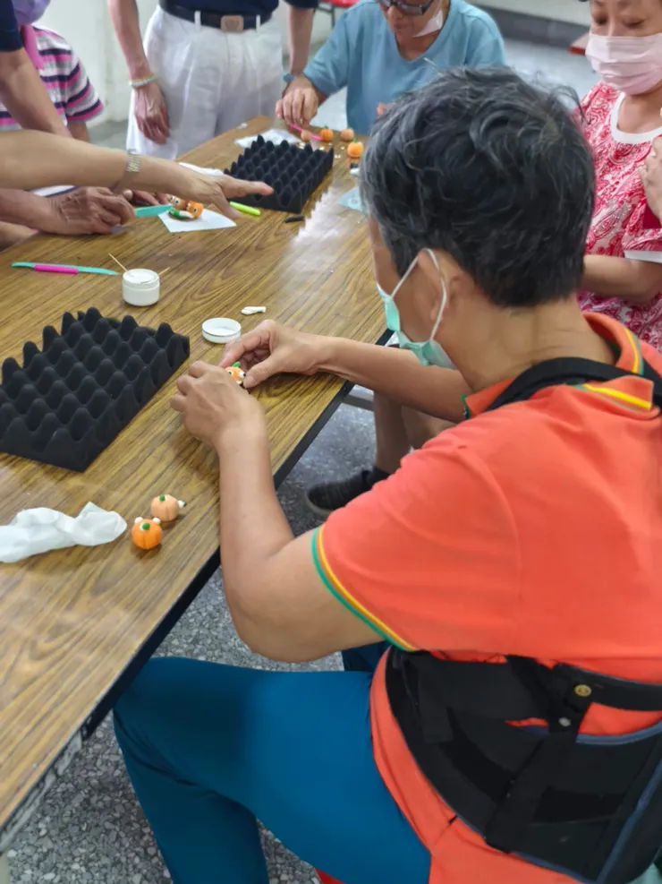 手作不分年齡。這位長輩雖然戴著護腰，但她那一雙歷經風霜的大手，正溫柔地捏塑著世界上最迷你的南瓜。