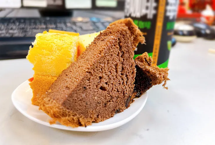 盤中切塊的初蛋糕豆漿蛋糕與巧克力蛋糕特寫，展示如海綿般蓬鬆綿密的切面質地，巧克力蛋糕內嵌豆漿夾心，呈現高含金量視覺感。