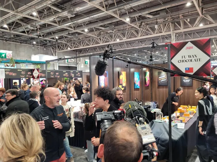 創辦人許華仁(中)於巴黎展位前受訪。圖/福灣巧克力提供