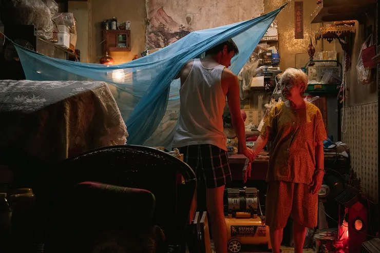 半夜驚醒的 M，默默守在阿嬤身旁，彷彿聽到阿嬤含淚的吶喊，M 的心裡也心如刀割般痛苦。來源：《金孫暴富攻略》電影劇照