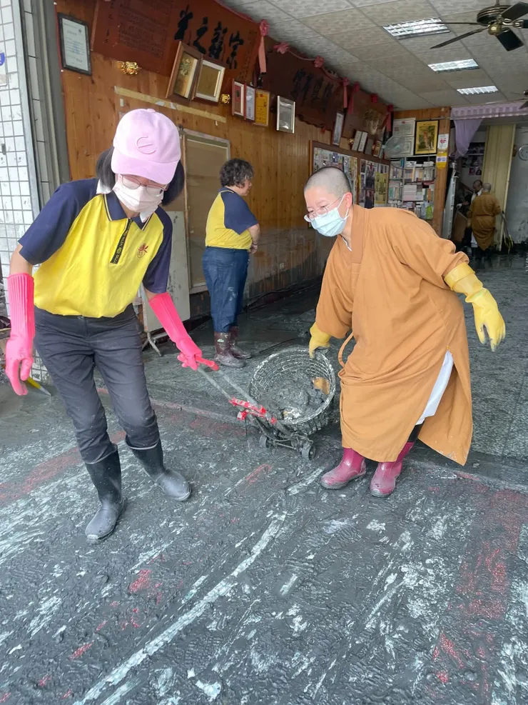 慈善團體的法師與義工，正在清掃泥沙。