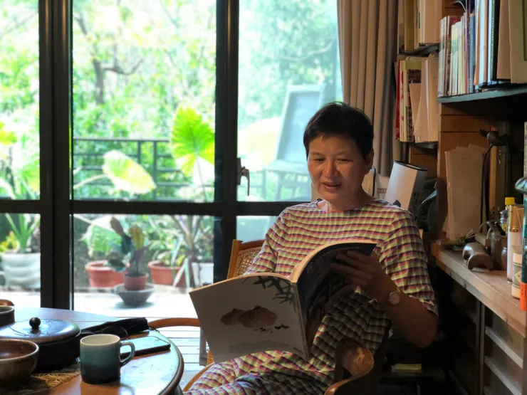 林秋芳翻著過去為桂竹林製作的成果專刊。攝影：郭旻純