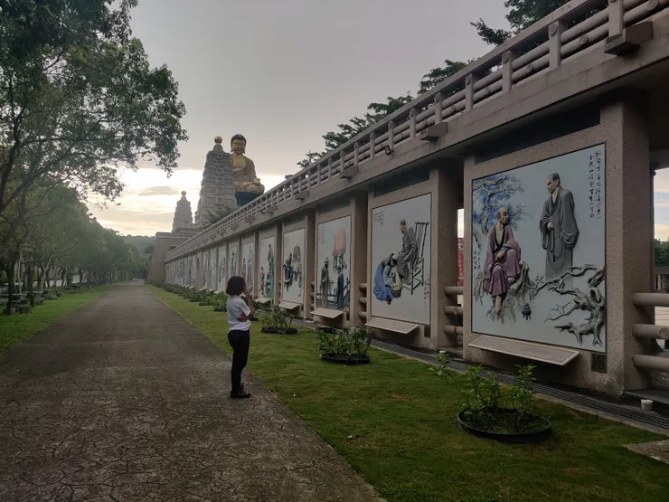 Estelle looking at the large-sized murals on the external walls flanking the Bodhi Wisdom Concourse