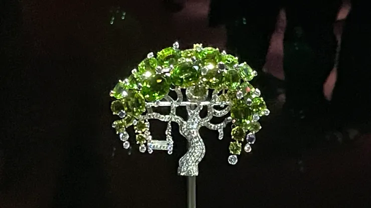 「幻想」胸針，白K金、黃K金、紫色藍寶石、橄欖石、鑽石，梵克雅寶在2008年推出的「花園」珠寶系列之一。 這款胸針以百年老樹為主體，樹頭枝椏鑲嵌了28顆橄欖石，還掛了一個鞦韆，會隨著佩戴者的動作而擺盪。 我一眼就愛上這棵樹，原本還以為它是生命之樹，蘊含神話意義咧。