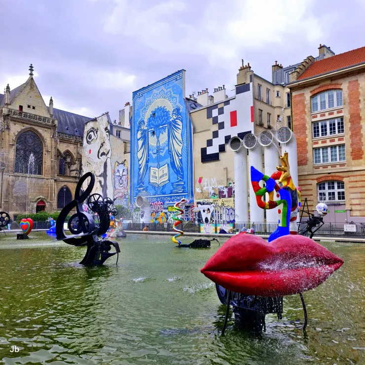 【史特拉汶斯基噴泉雕塑繽紛有趣！在龐畢度中心（Centre Pompidou）旁邊的史特拉汶斯基廣場（Place Stravinsky）。背景可見4支白色的巨大通風管，左邊建築為約800年歷史的聖梅里教堂（Saint-Merri Church）。】