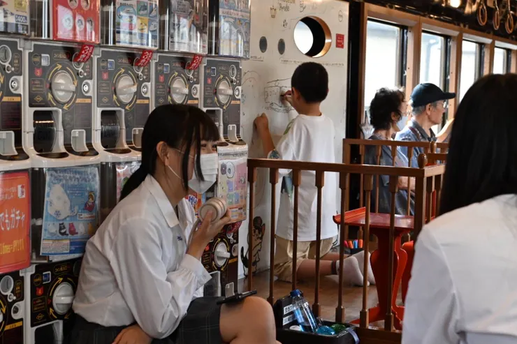 當地學生坐在車上的扭蛋機前閒聊著，一旁的弟弟則是在白板上畫畫，呈現了兼用型列車會出現的經典畫面。/攝影:NANA濕婦