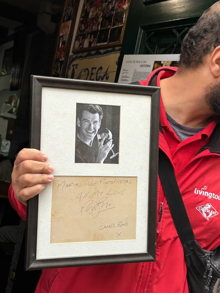 在街上招攬客人的酒吧老闆，拿出傳家寶─詹姆士龐德的簽名來吸引眼球。