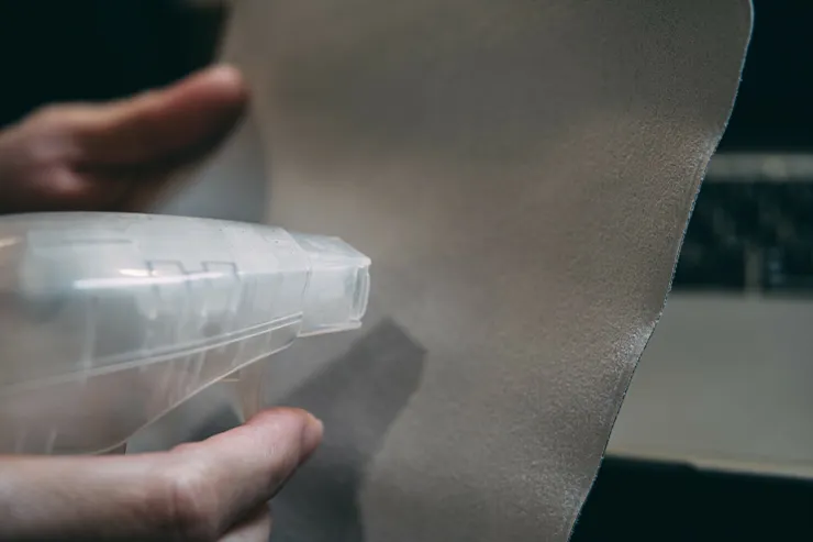 將清潔用液體(或水)噴灑在擦拭布上