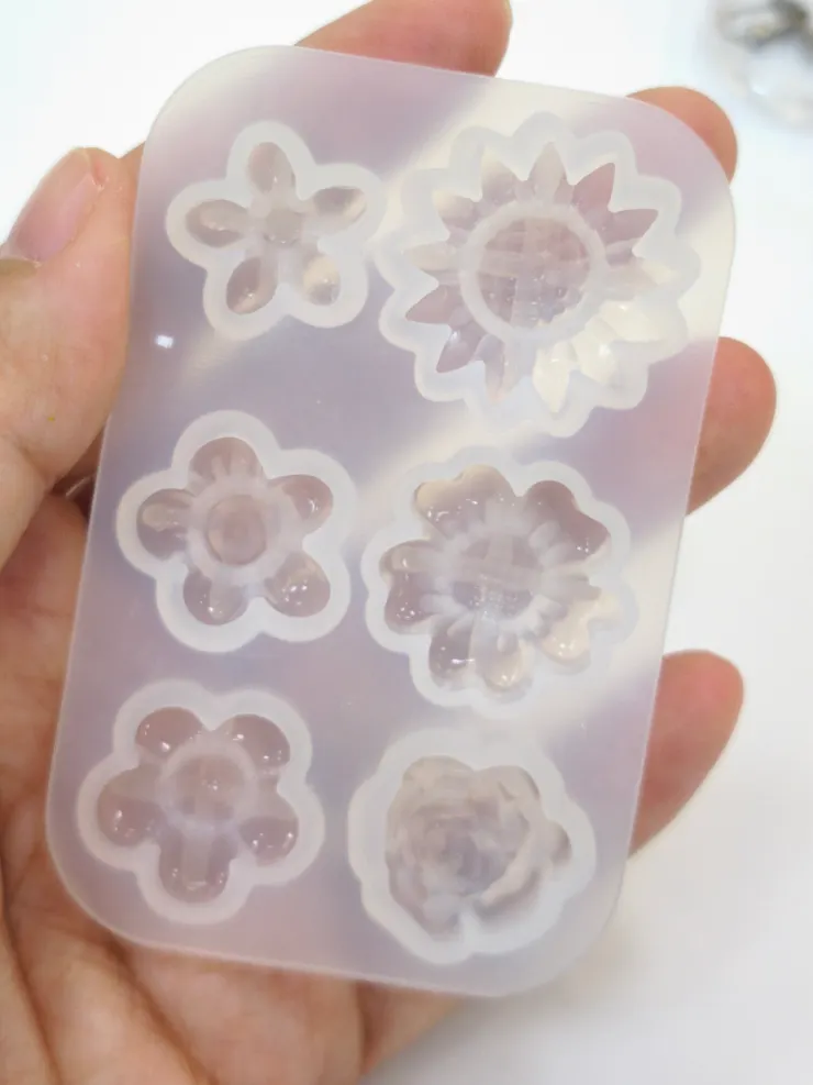 🌼步驟2：組合花朵  花芯先用剛才預留的小塊軟陶，往矽膠模具填補，即完成花芯。  再用剛才捲好的蝸牛殼狀的軟陶，往矽膠模具填補，即完成花瓣。