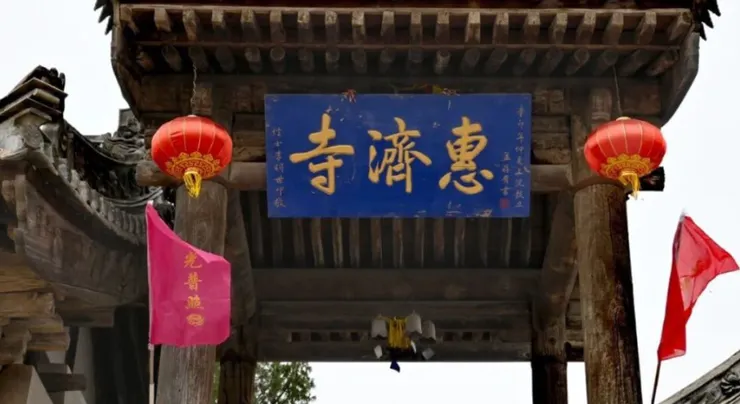 慧濟寺的正門上掛著藍色的匾額，上面書寫著「惠慈寺」字樣，兩側紅燈籠掛在門柱上，增添了幾分莊嚴與神聖。