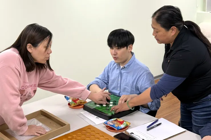 （圖說：在伊甸視障服務中心主任周玉玲(左)引導下，貴賓體驗遊玩「盲用圍棋」。）