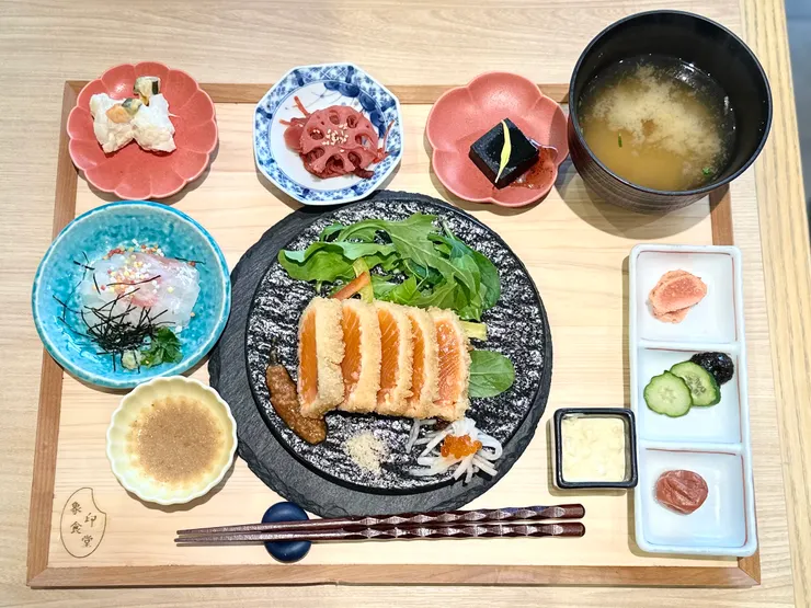 雖然牛豬雞也吸引，但還是挑了相對少見的吉列三文魚拼鯛魚茶泡飯，定食規格，配菜有塊黑黑的糕點不知道是什麼，但味道很正常（可能是墨魚汁？）醃物與椰菜花味道也不錯。