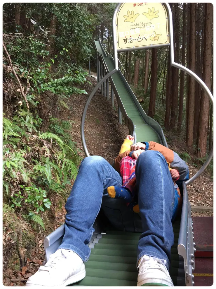 孩子的爸抱孩子溜下來的休息狀態，因為要溜這一趟得爬一段山坡。照片無法呈現整段溜滑梯的面貌。爸爸累了😂〔日本遊戲場〕