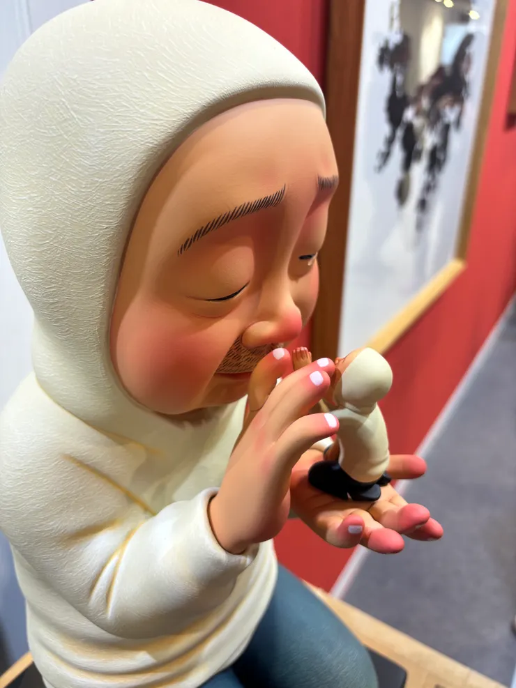 大人與小人的互動：大人托起小小的自己，小人輕撫大人的臉，象徵內心自我療癒的對話。