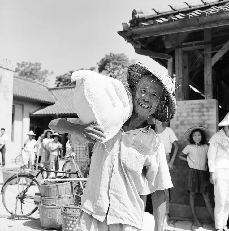 領取救濟麵粉。1963年，台灣重要農產品鳳梨因霜災而損失慘重，農民心血付之一炬。政府為幫助農民度過此一難關，因此大量收購鳳梨，並發放美援所提供之救濟麵粉，農民在領取到賴以維生的麵粉後，莫不露出欣慰的笑容。（圖片來源：國家文化記憶庫）