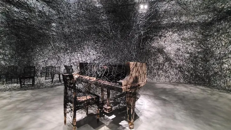 取自中央廣播電臺 塩田千春「靜默中」,2002/2021,燒焦鋼琴、燒焦椅、Alcantara黑線。(江昭倫攝)