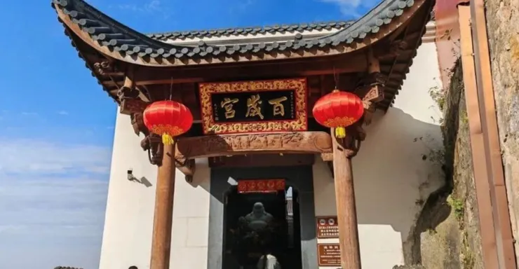 百歲宮的入口,紅色燈籠高懸,匾額上的「宮殿百年」字樣顯眼,精緻的木結構與屋頂勾勒出傳統的建築風格。