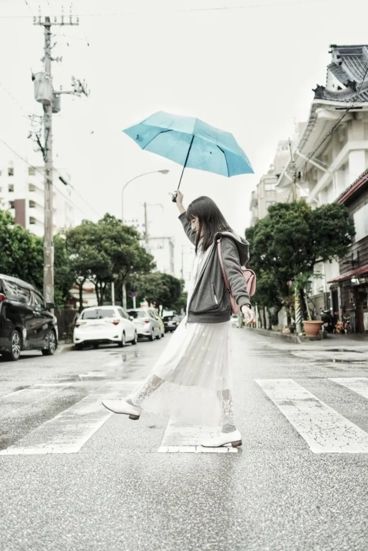 白色的街景和白灰色的人和藍色的傘