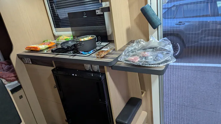 小小的廚房，瓦斯爐旁有延伸桌面、上面有微波爐、下面是冰箱