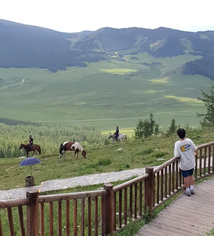 下山的步道旁,草坡上有人在騎馬,馬兒悠閒在吃草,美得像一幅畫