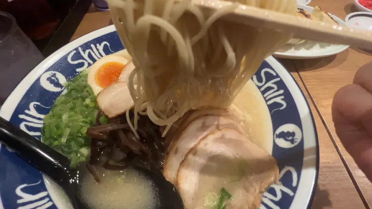 筷子夾起吸飽濃郁湯汁的講究極細平打麵。