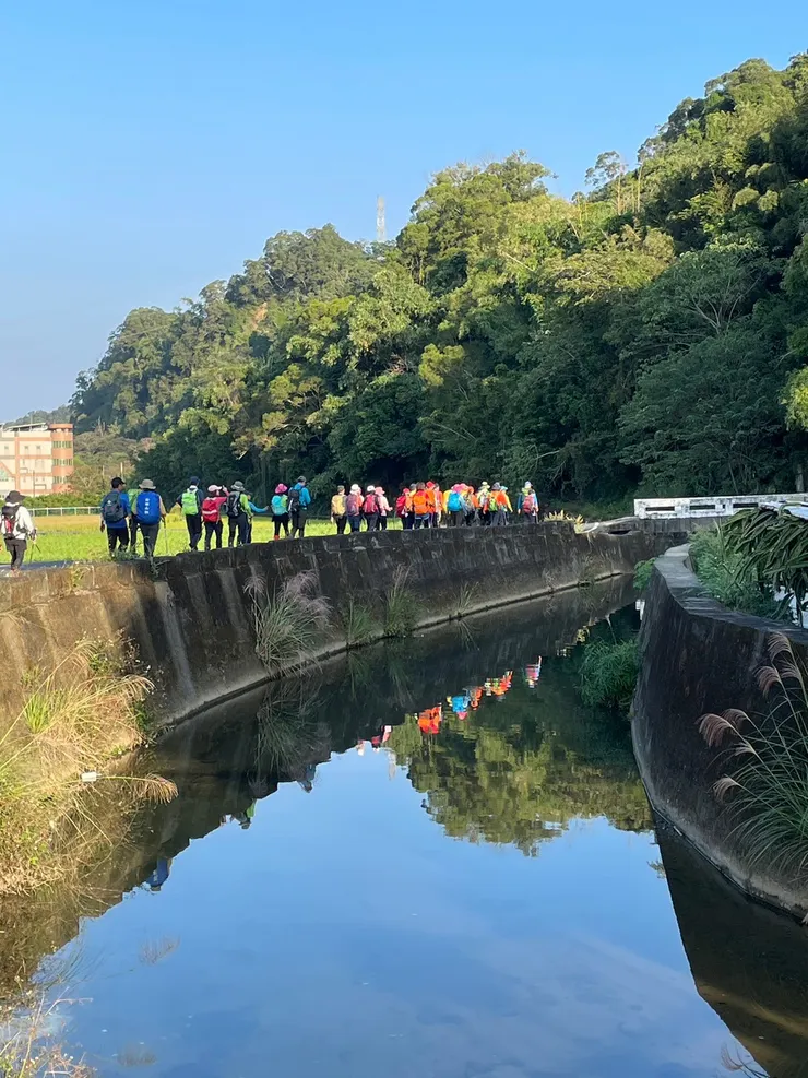 啟登不久行經水圳，水靜如鏡映出漂亮隊伍