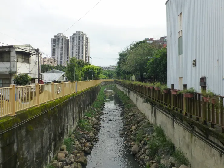 圖示:台灣新北土城公館溝,遠處有新建的住宅大樓。圖片來源為張居隱:https://www.shutterstock.com/zh/image-photo/2418060295