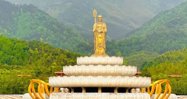 大願文化園區，金色佛像矗立在潔白的蓮花座上，背景是青山綠樹，展現出寧靜且莊嚴的景觀