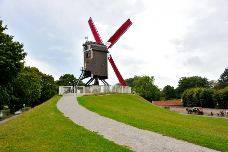 【出民宿直向東尋訪十字門與風車 小丘草地林蔭道左望古城右運河!Sint-Janshuismolen,它開放購票參觀,但想必樓梯陡直難爬,我們没進去。照片右下角有兩輛觀光馬車帶來一票遊客準備入內參觀。】