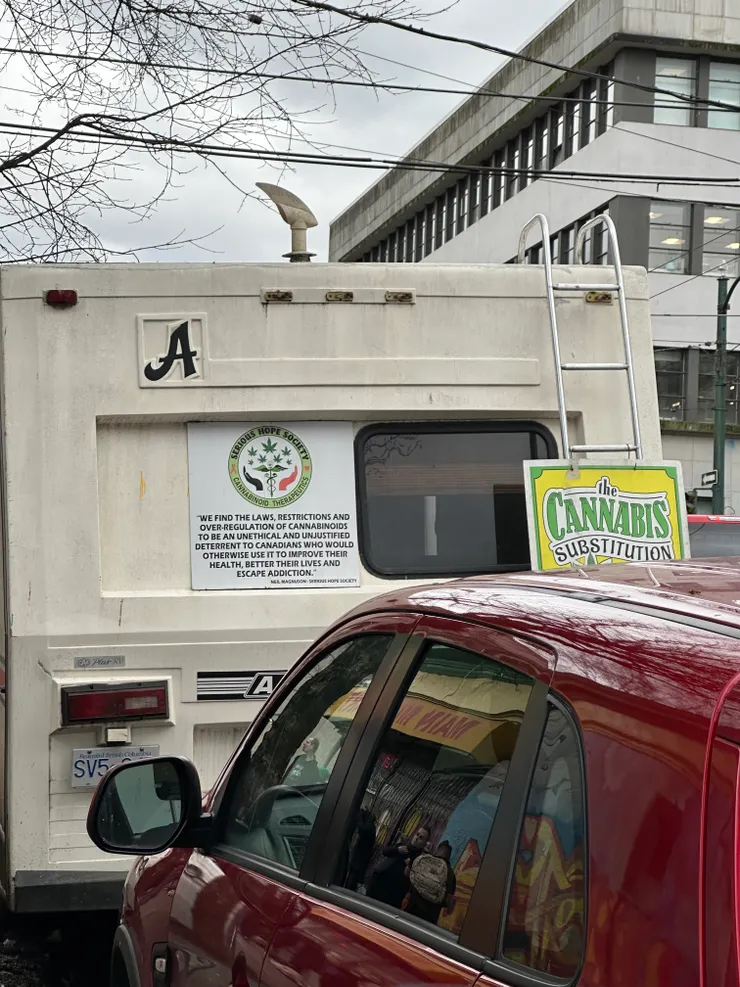 路上的車子，從車窗反射可以看到街邊的人們。