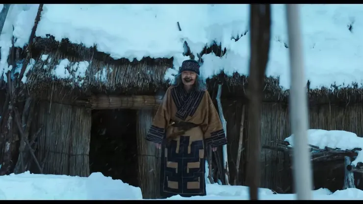 電影裡阿席莉帕的外祖母(阿伊努語：呼奇)身著傳統服飾站在屋前，圖片來源：Netflix