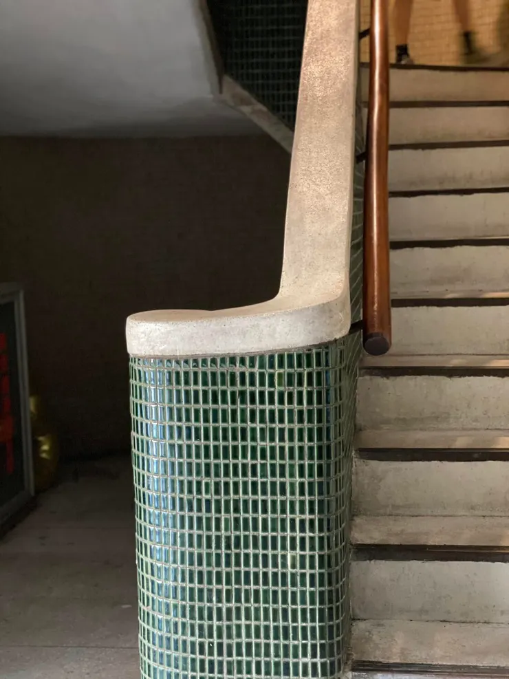 樓梯座貼覆橄欖綠色的馬賽克磁磚，扶手這一截則更換為磨石子