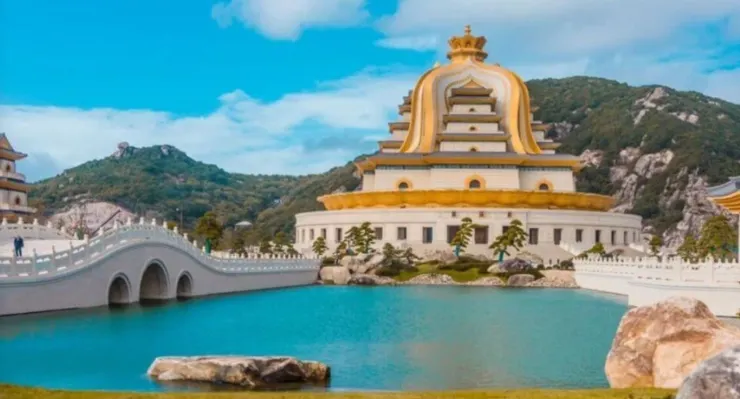 一座宏偉的觀音寺廟，寺廟的金色屋頂與周圍的湖泊和綠意盎然的景色相互映襯。