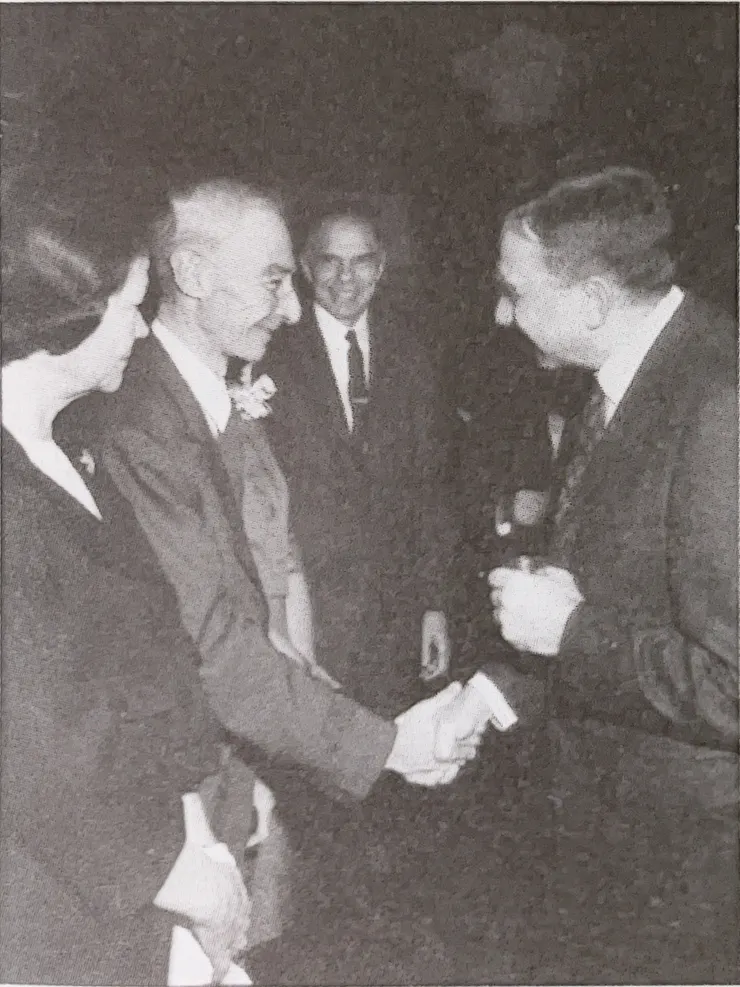 1963奧本海默獲頒費米獎,愛德華泰勒走向奧本海默恭喜他獲獎,基蒂則面無表情站在丈夫身邊(照片來源:筆者翻攝自《奧本海默》(下)國家英雄殞落。時報出版 2023