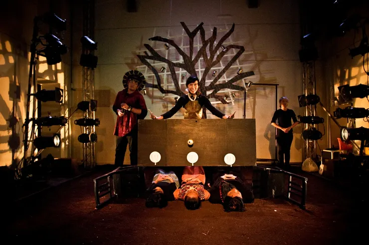 ▲開場是女媧和耶和華的歌舞秀,一家人被桌子壓在下面,吃著寒酸的晚餐。(天氣滿冷的,演出期間前半,演員躺在濕濕的土中受寒,後半,土變乾了但又會塵土飛揚,導致演到後來喉嚨超乾、鎖喉、強忍咳嗽,真是太敬業了!舞台設計王永宏辛苦找來兩種土調出是合的顏色。)